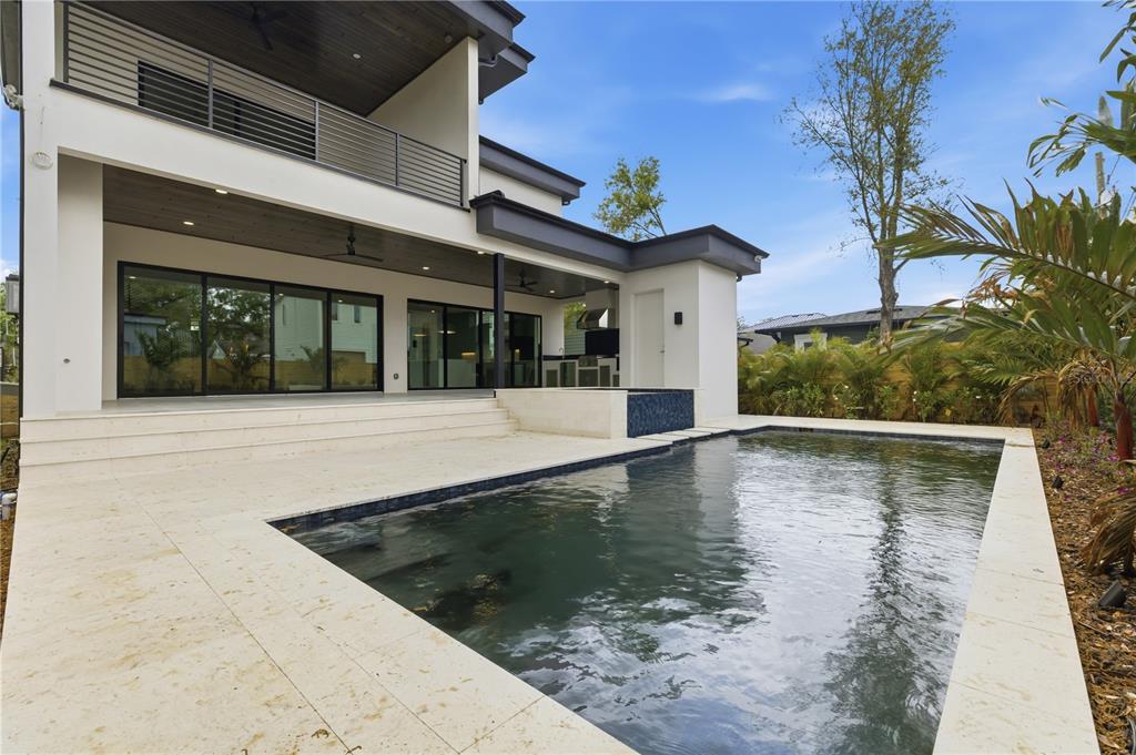 A modern two-story house features a covered patio, swimming pool, and light-colored stone decking — 2203 GLENWOOD, TAMPA, FL