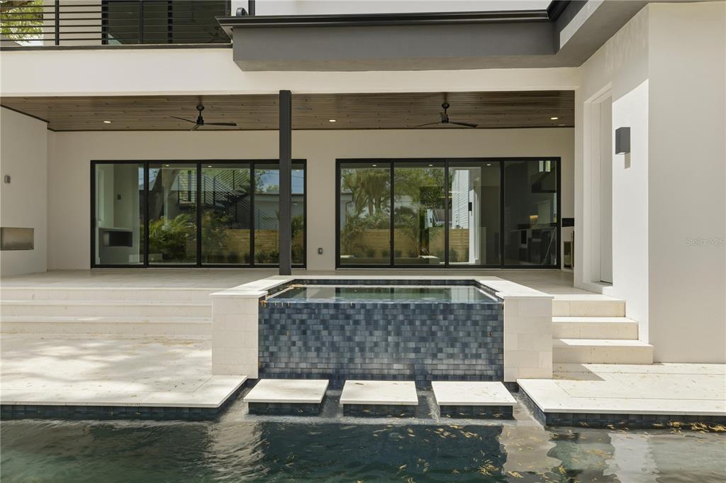 A modern patio features a tiled hot tub, a swimming pool, and large sliding glass doors — 2203 GLENWOOD, TAMPA, FL