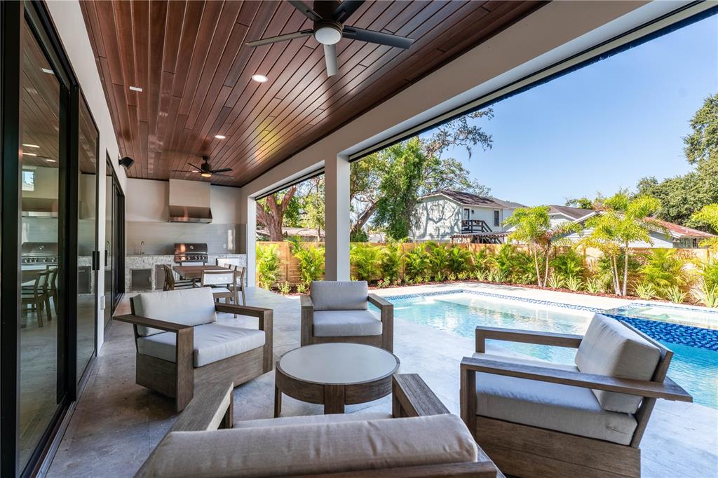 A covered patio features wood-paneled ceilings, outdoor seating, and an adjacent pool and kitchen area — 2203 GLENWOOD, TAMPA, FL
