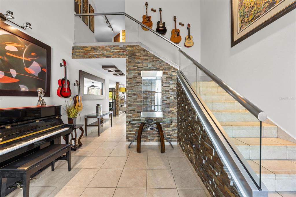 A foyer features a piano, stone accent wall, glass-railed staircase, and guitars displayed on walls — 677 PASEO LOS CORALES I, MAR INDICO ST UNIT F-10, DORADO, PR