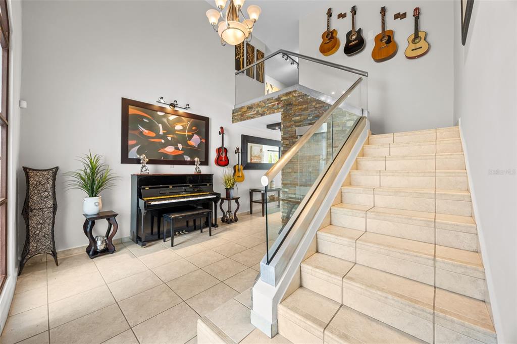 A foyer features a piano, a tiled staircase with a glass railing, and wall-mounted guitars — 677 PASEO LOS CORALES I, MAR INDICO ST UNIT F-10, DORADO, PR