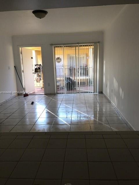 A room with white walls, light-colored tile flooring, and a sliding glass door to a patio — 15401 SW 81st Cir Ln # 16, Miami FL 33193, MIAMI, FL