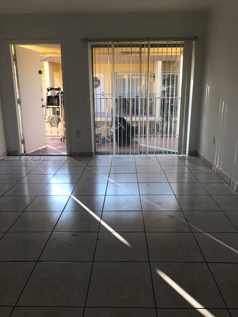 An interior room with white tile flooring, a doorway, and a sliding glass balcony door — 15401 SW 81st Cir Ln # 16, Miami FL 33193, MIAMI, FL