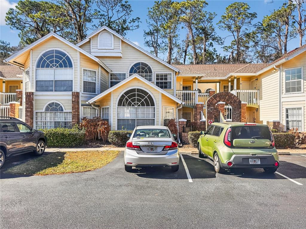 A two-story apartment building with yellow siding, arched windows, and a parking lot in front — 5005 LAGUNA BAY CIRCLE UNIT 22, KISSIMMEE, FL