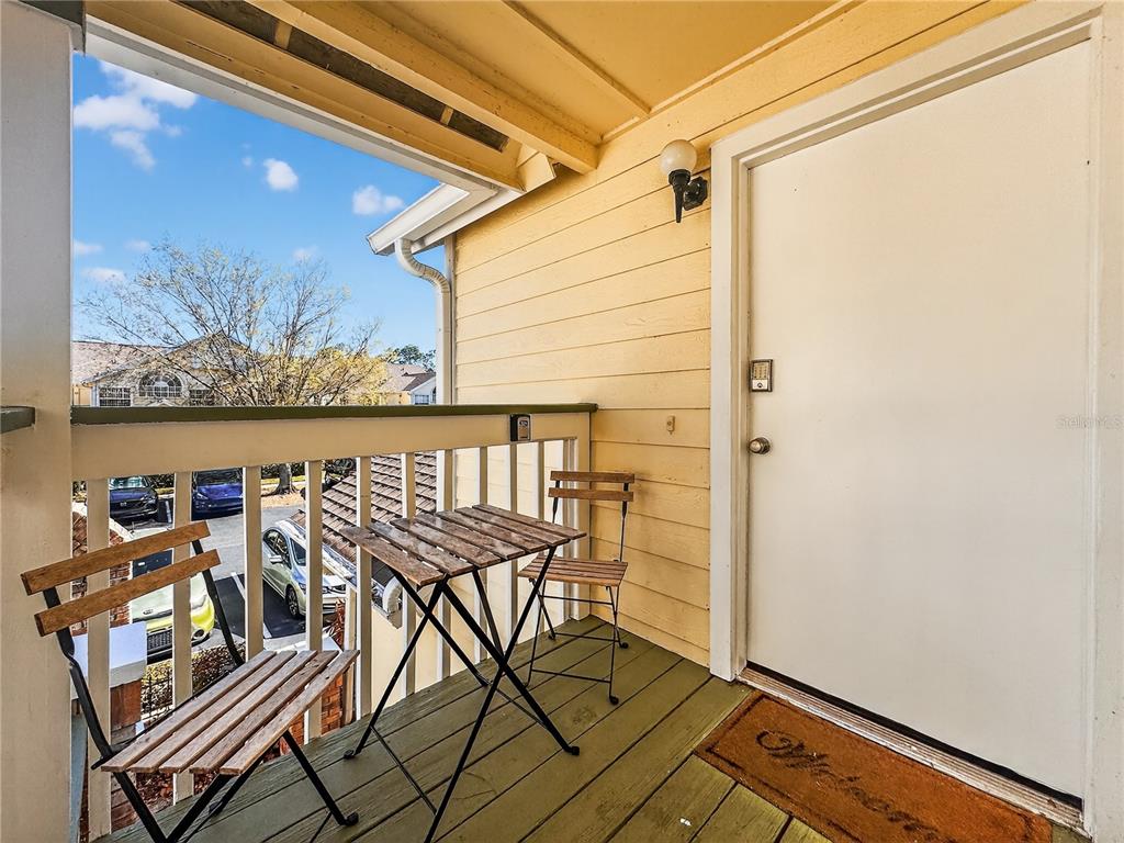 A small balcony features a wooden table, two folding chairs, and a white entry door — 5005 LAGUNA BAY CIRCLE UNIT 22, KISSIMMEE, FL
