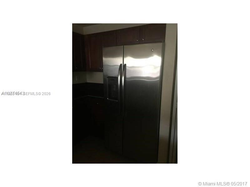 A stainless steel side-by-side refrigerator is installed in a kitchen with dark wood cabinets — 11601 NW 89th St # 107, Doral FL 33178, DORAL, FL