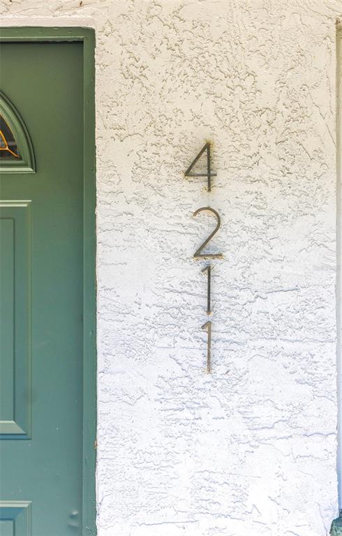 A vertical house number 4211 is mounted on a white textured wall beside a green door — 4211 W BAY VIEW AVENUE, TAMPA, FL
