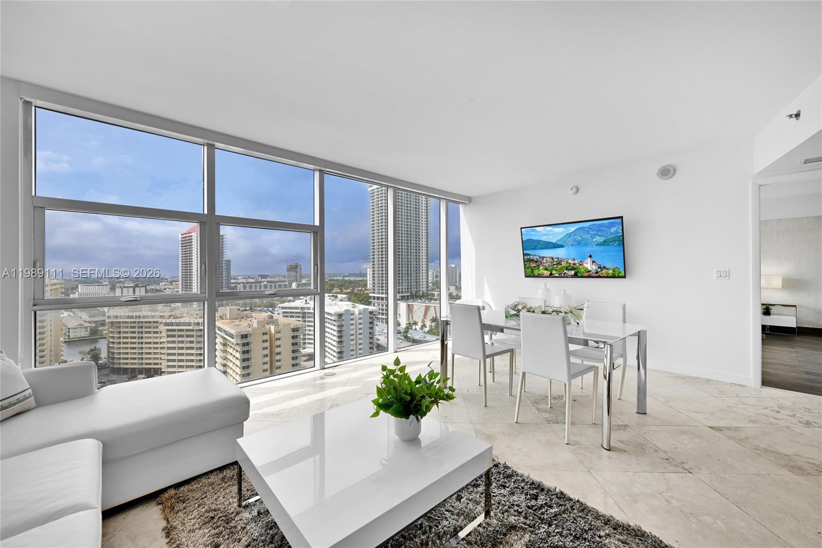 A bright living and dining area features floor-to-ceiling windows with city views and tile flooring — 1830 S Ocean Dr # 1907, Hallandale Beach FL 33009, HALLANDALE BEACH, FL