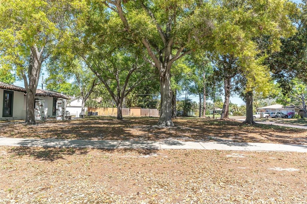 A vacant, tree-covered residential lot sits next to a house with a tile roof — 6201 11TH AVENUE S, GULFPORT, FL