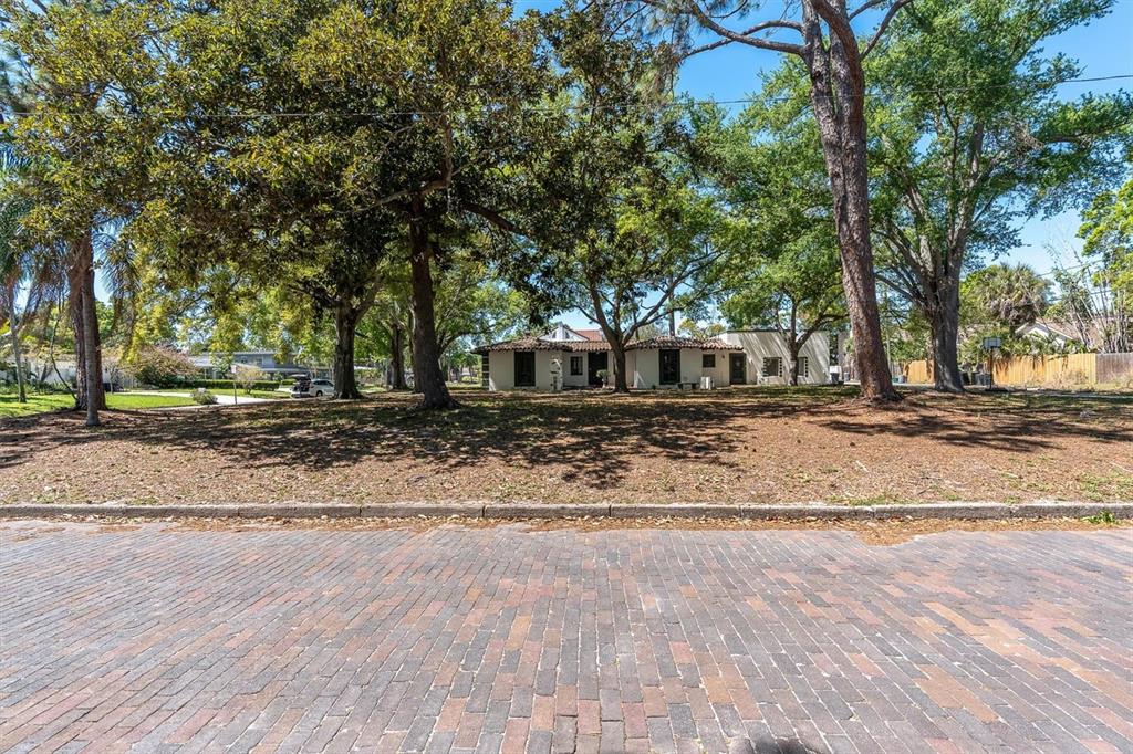 A single-story house with a tiled roof sits behind a large, tree-shaded dirt yard — 6201 11TH AVENUE S, GULFPORT, FL
