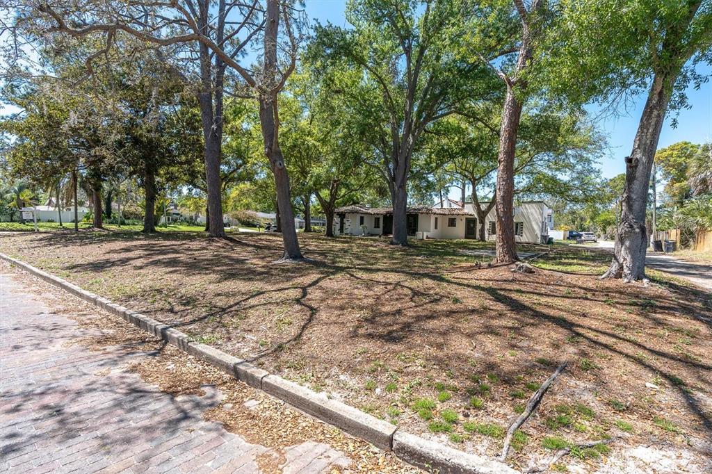 A large, tree-filled lot with a single-story house in the background and brick street — 6201 11TH AVENUE S, GULFPORT, FL