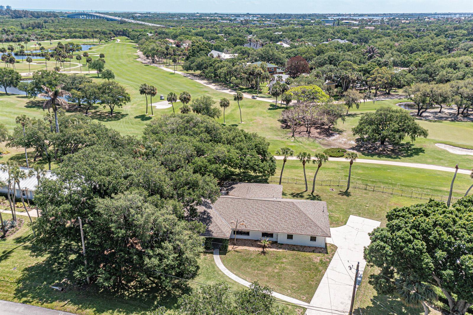 An aerial view shows a single-story house with a shingled roof bordering a golf course — 3360 Buckinghammock Trail, Vero Beach FL 32960, VERO BEACH, FL