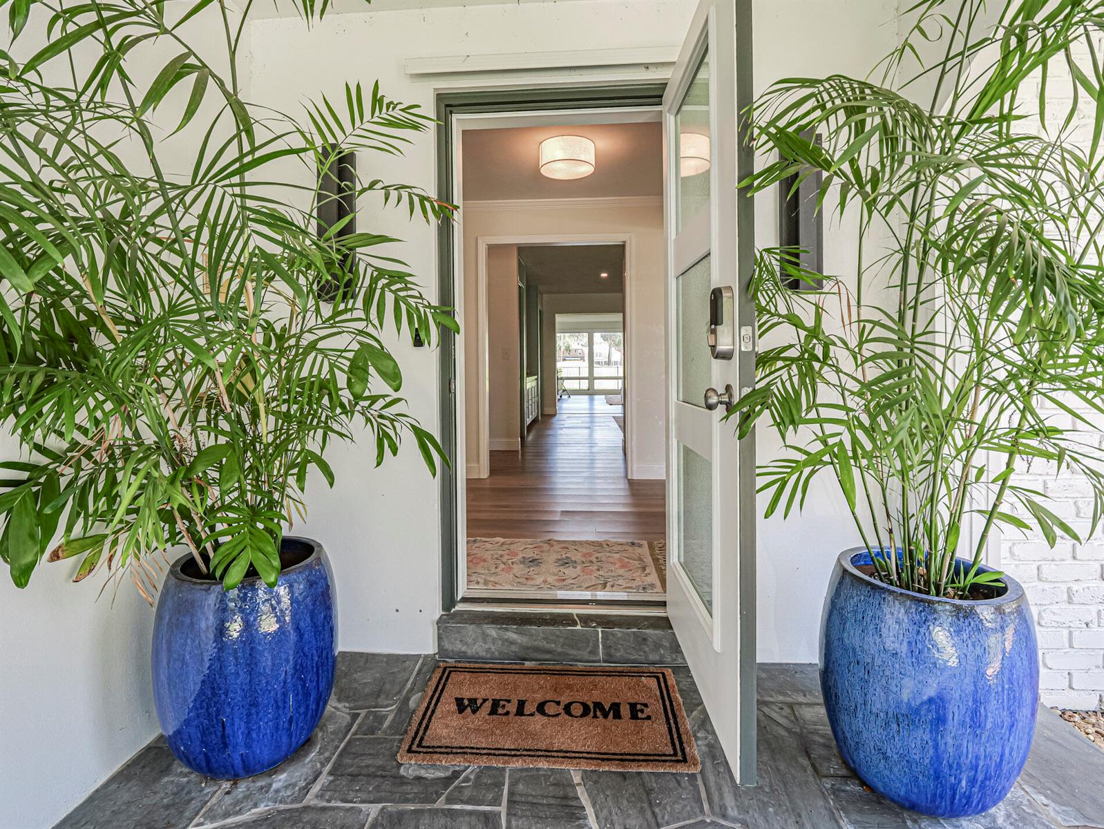 An open front door reveals a view into a home with hardwood floors and plants — 3360 Buckinghammock Trail, Vero Beach FL 32960, VERO BEACH, FL