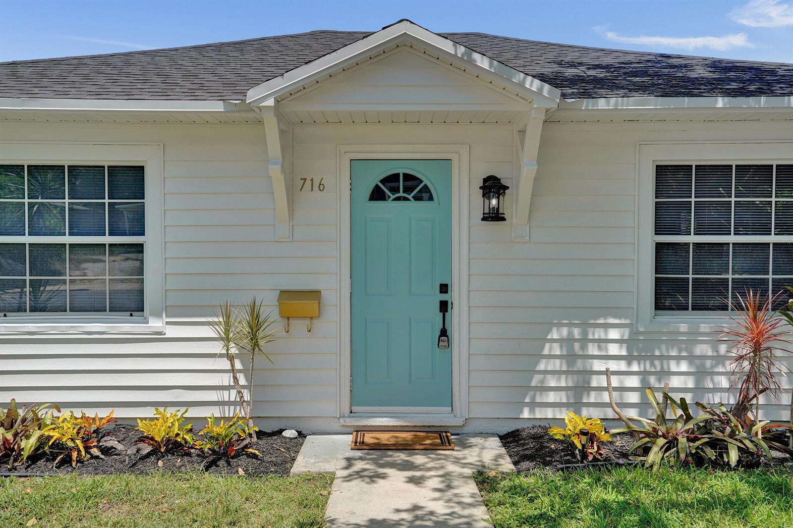 A white house exterior features a light blue front door and a small covered entryway — 716 S Pine Street, FL 33460, FL