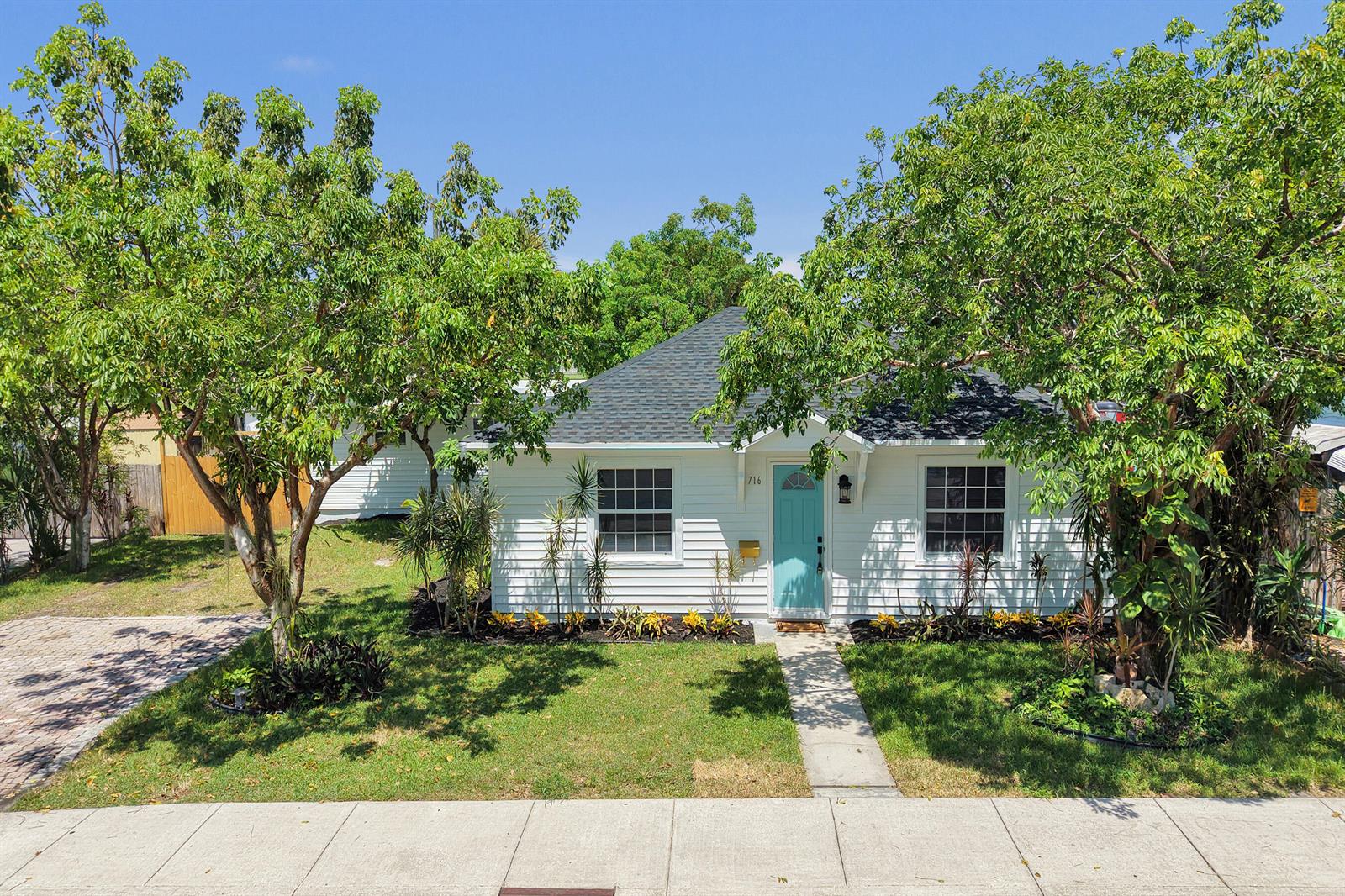 A white single-story house with a turquoise front door and a dark shingled roof — 716 S Pine Street, FL 33460, FL