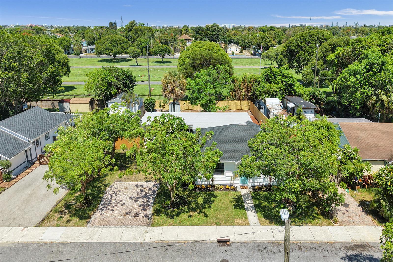 An aerial view shows a white house with a dark roof, trees, and a paved driveway — 716 S Pine Street, FL 33460, FL