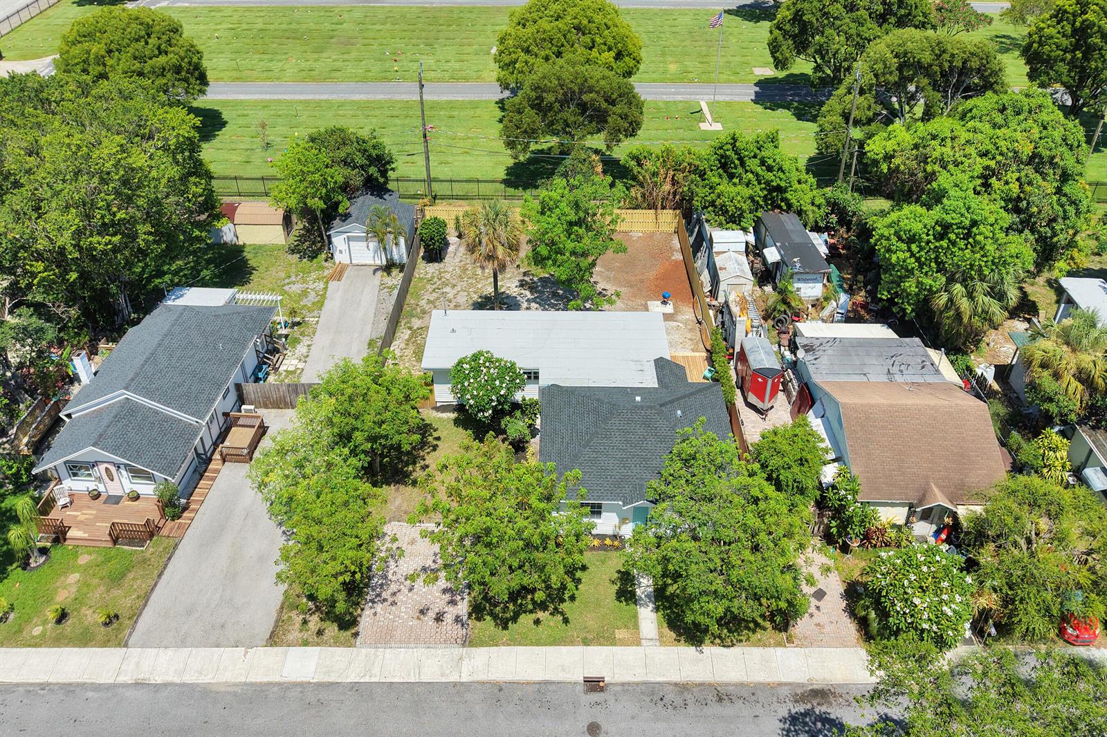 An aerial view shows three residential houses with driveways and trees in a suburban neighborhood — 716 S Pine Street, FL 33460, FL