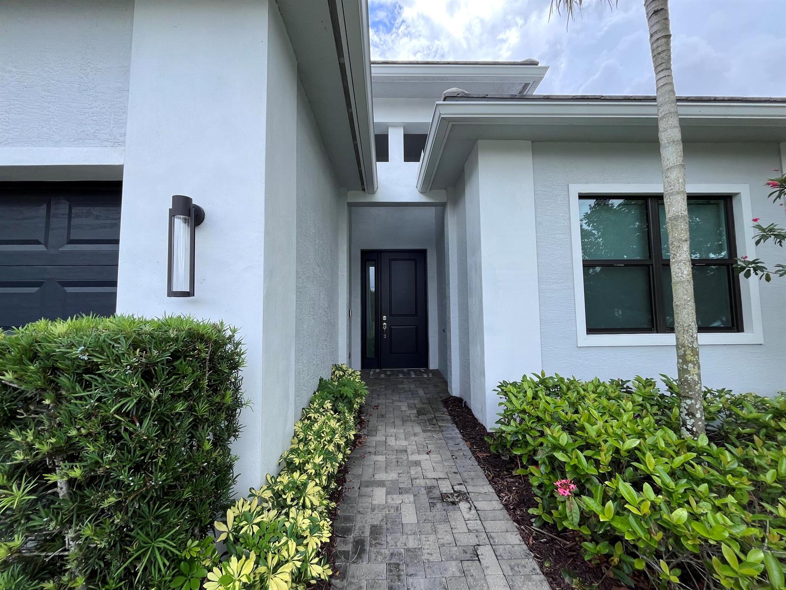 A paved walkway leads to the dark front door of a white stucco house — 5663 Saint Armands Way, FL 33470, FL