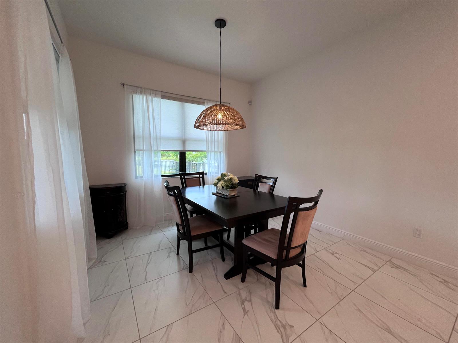 A dining room with a dark wood table, four chairs, and a woven pendant light — 5663 Saint Armands Way, FL 33470, FL