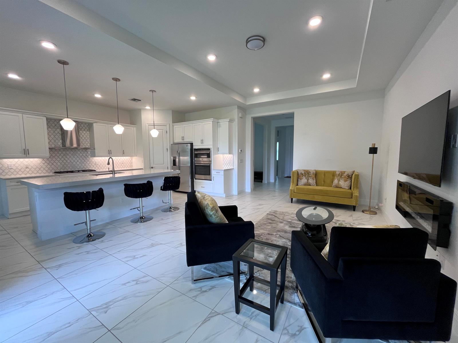 An open-concept kitchen and living area features white cabinetry, marble-look tile floors, and modern furniture — 5663 Saint Armands Way, FL 33470, FL