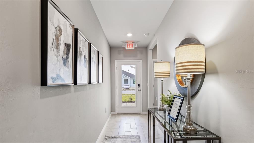 A hallway features framed wall art, a console table with lamps, and a glass-paneled door — 26263 CORAL LAKES DRIVE, PUNTA GORDA, FL