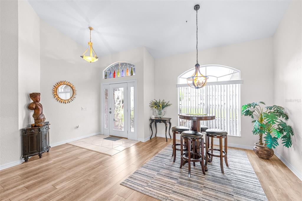 A bright dining area features wood-look flooring, a round table with stools, and an entryway — 6546 BENDELOW DRIVE, LAKELAND, FL
