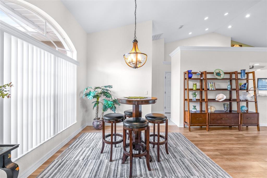 A dining area features a round table with three stools, a chandelier, and a bookshelf — 6546 BENDELOW DRIVE, LAKELAND, FL