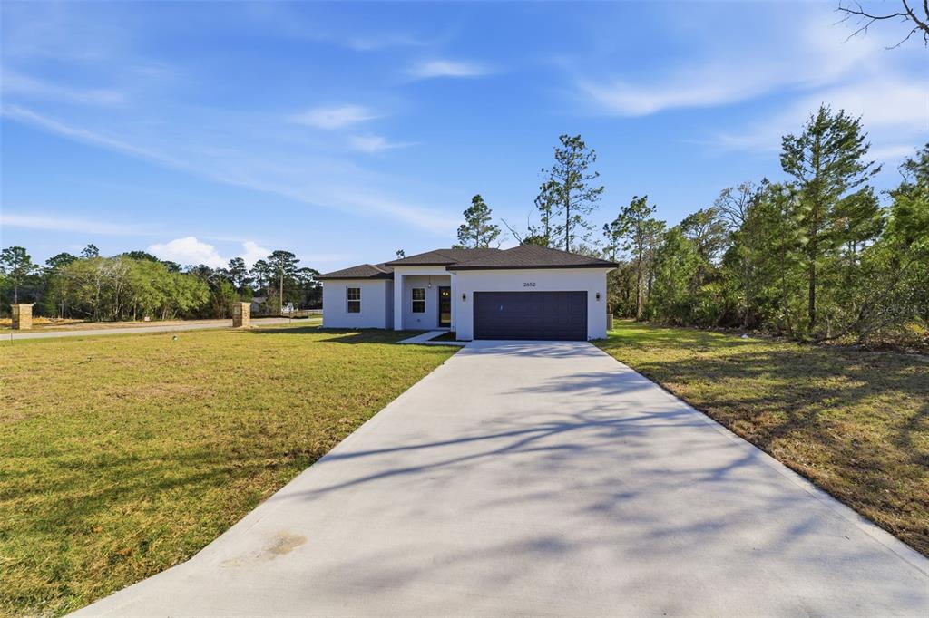 A single-story house with a dark garage door and a concrete driveway sits on a lot — 2652 W PARAGON LANE, DUNNELLON, FL