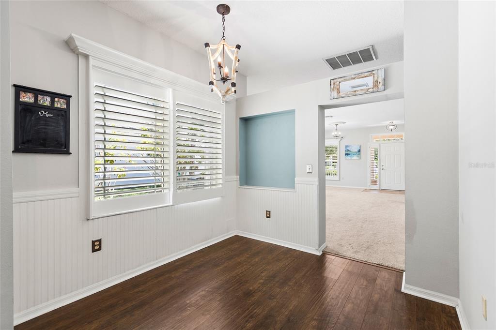 A dining area features dark wood floors, white wainscoting, plantation shutters, and a light fixture — 19218 SEA MIST LANE, LUTZ, FL