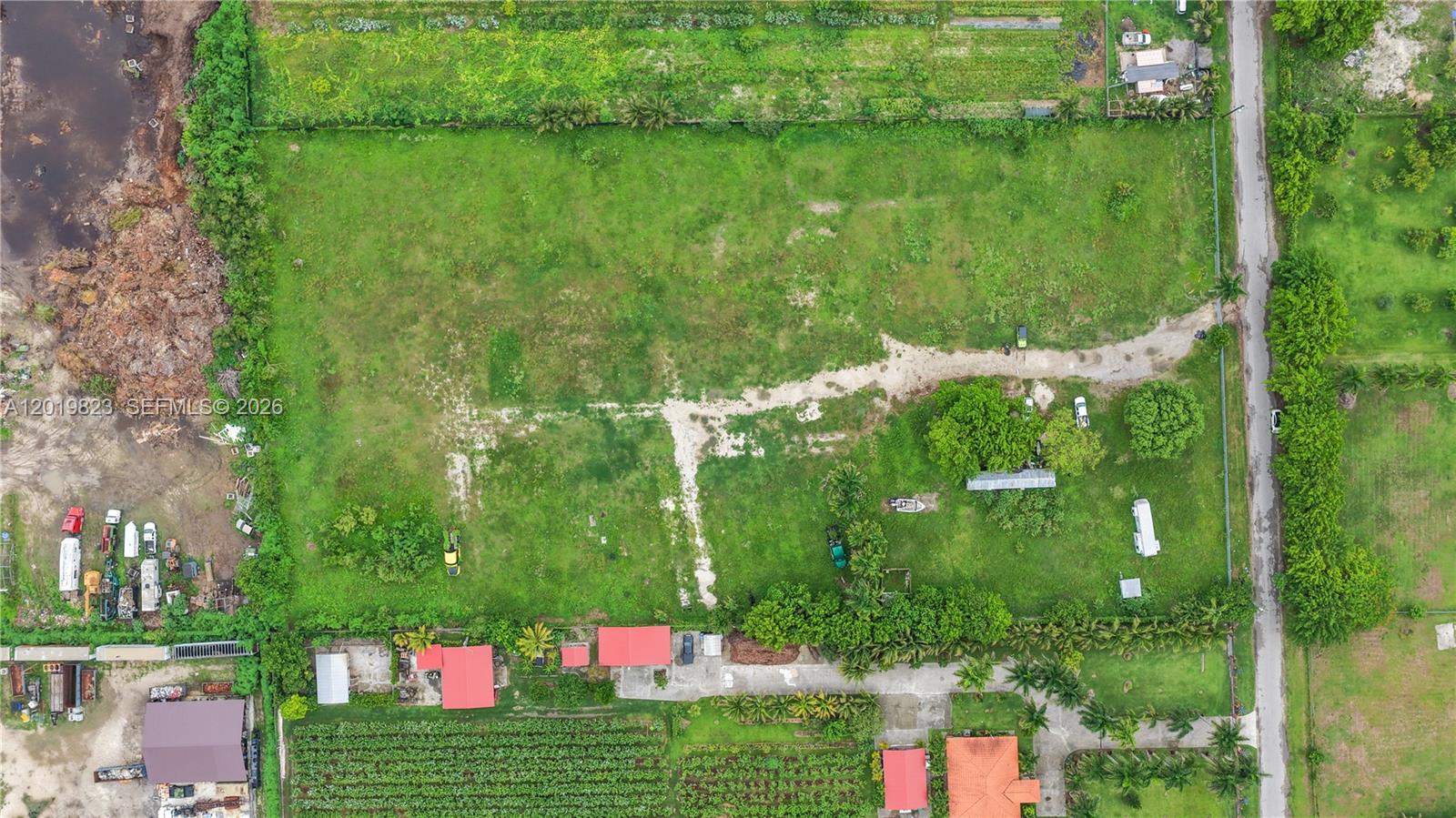 An aerial view shows a large, grassy rectangular lot with scattered trees and structures — UNINCORPORATED DADE COUNTY, FL