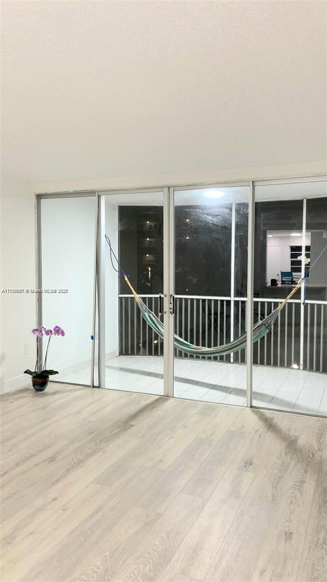 A room with light wood-look flooring features a sliding glass door leading to a balcony — 1670 NE 191st St # 3, Miami FL 33179, MIAMI, FL