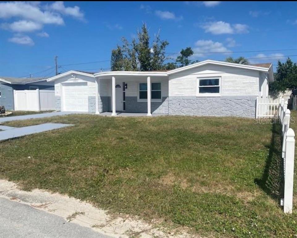 A single-story house with a white garage, a curved porch, and a concrete driveway — 4803 GUARDIAN AVENUE, HOLIDAY, FL