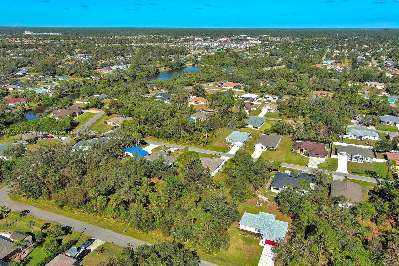 An aerial view shows a suburban neighborhood with houses, trees, and a small lake — #2 Sargon Ave, North Port FL 34287, NORTH PORT, FL