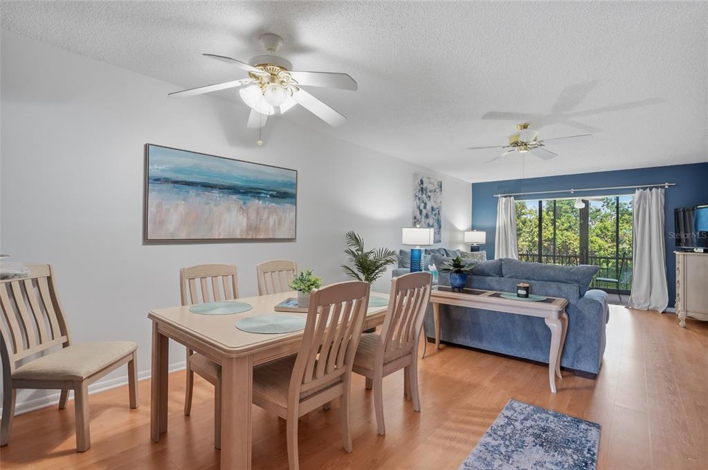 A dining area with a light wood table and chairs opens into a blue-walled living room — 1624 STICKNEY POINT ROAD UNIT 1624-208, SARASOTA, FL
