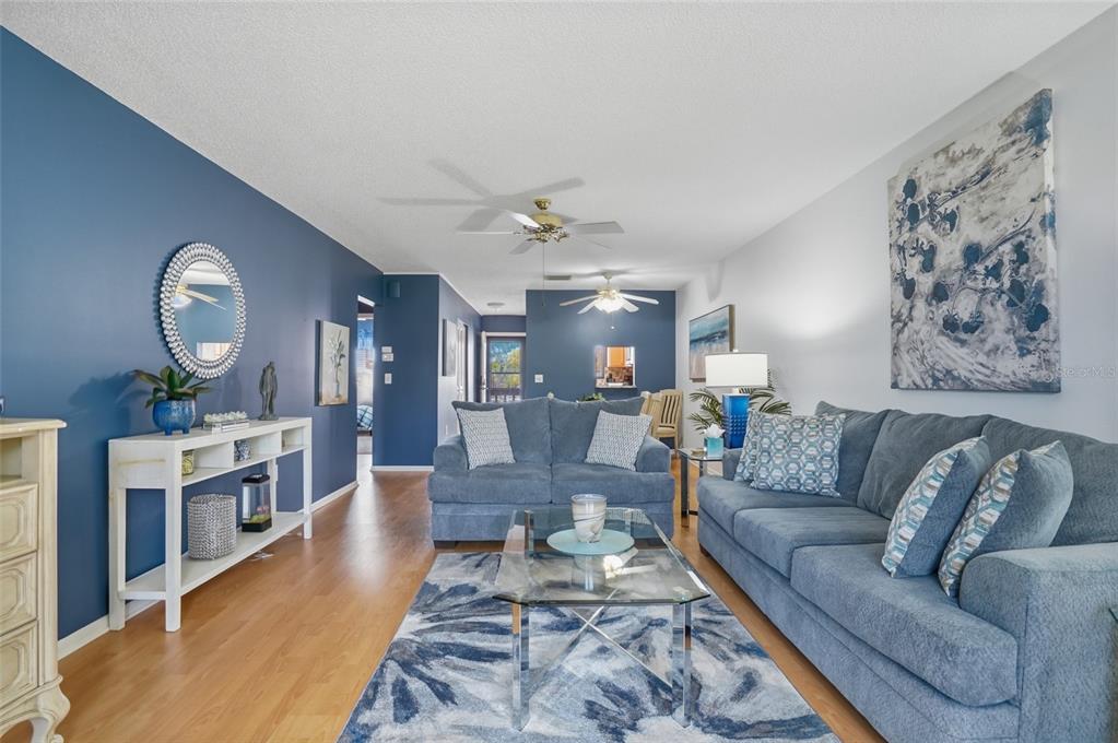 A living room features blue walls, a blue sofa, a glass coffee table, and wood flooring — 1624 STICKNEY POINT ROAD UNIT 1624-208, SARASOTA, FL