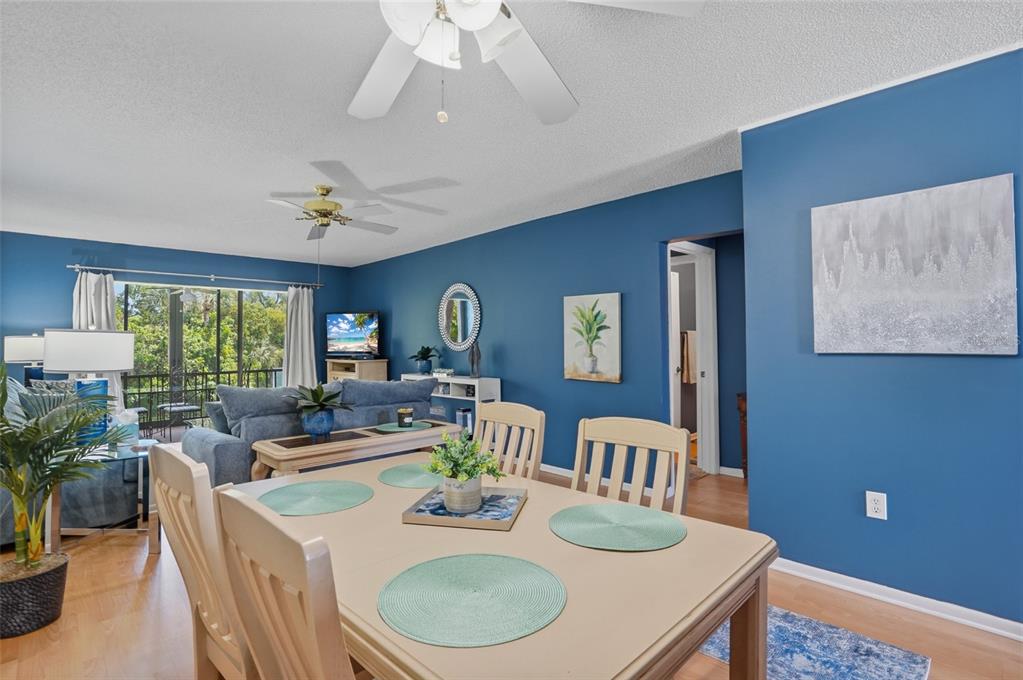 A dining area with a light-colored table sits in front of a blue-walled living room — 1624 STICKNEY POINT ROAD UNIT 1624-208, SARASOTA, FL