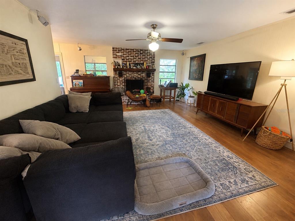 A living room features a large sectional sofa, a brick fireplace, and a television console — 308 N SALISBURY AVENUE, DELAND, FL
