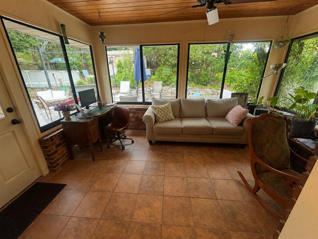 A sunroom features tile flooring, a beige sofa, a desk, and large windows overlooking a yard — 308 N SALISBURY AVENUE, DELAND, FL