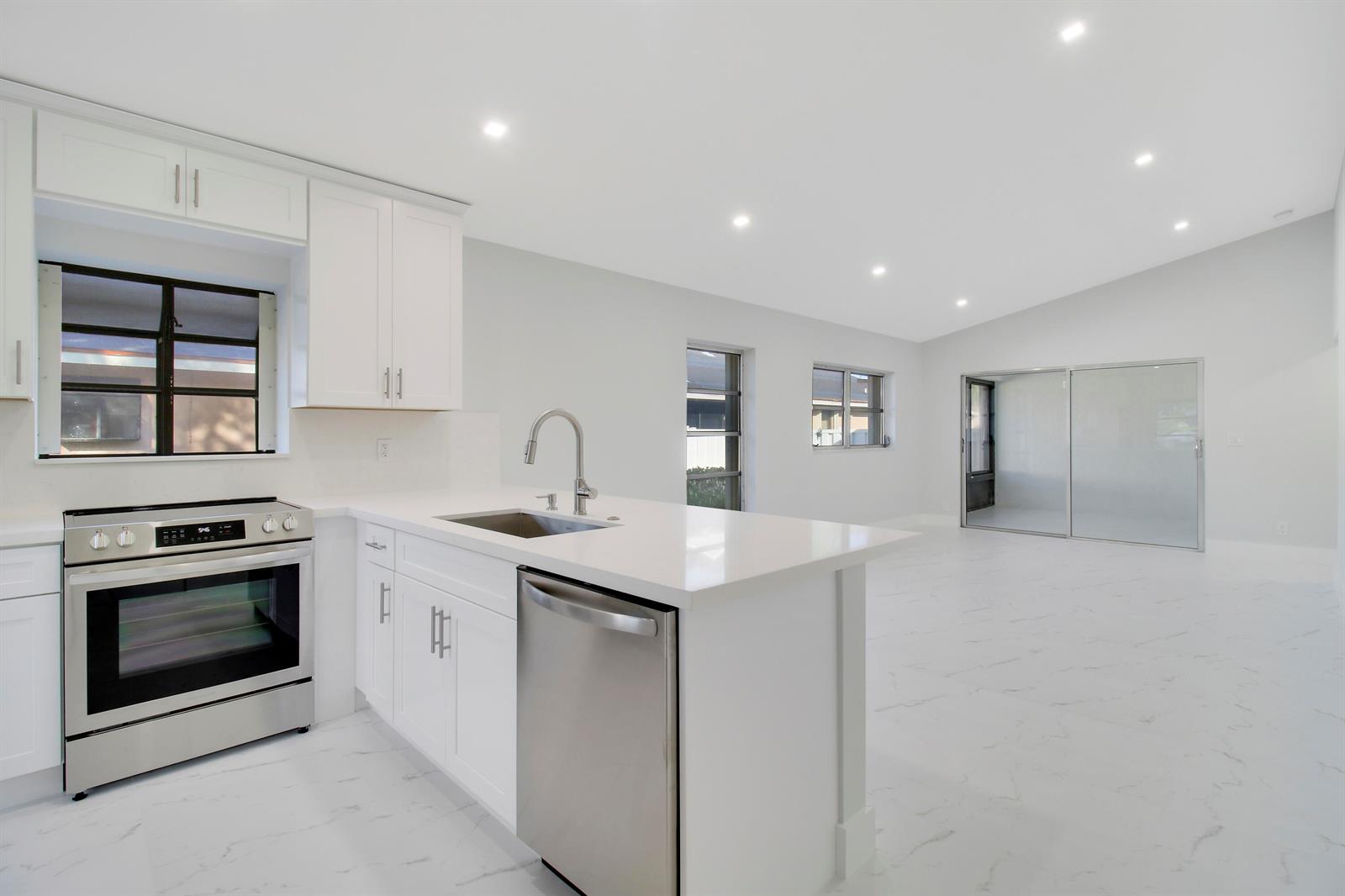 A modern kitchen features white cabinets, stainless steel appliances, and white marble-patterned tile flooring — 8055 Sweetbriar Way, Boca Raton FL 33496, BOCA RATON, FL