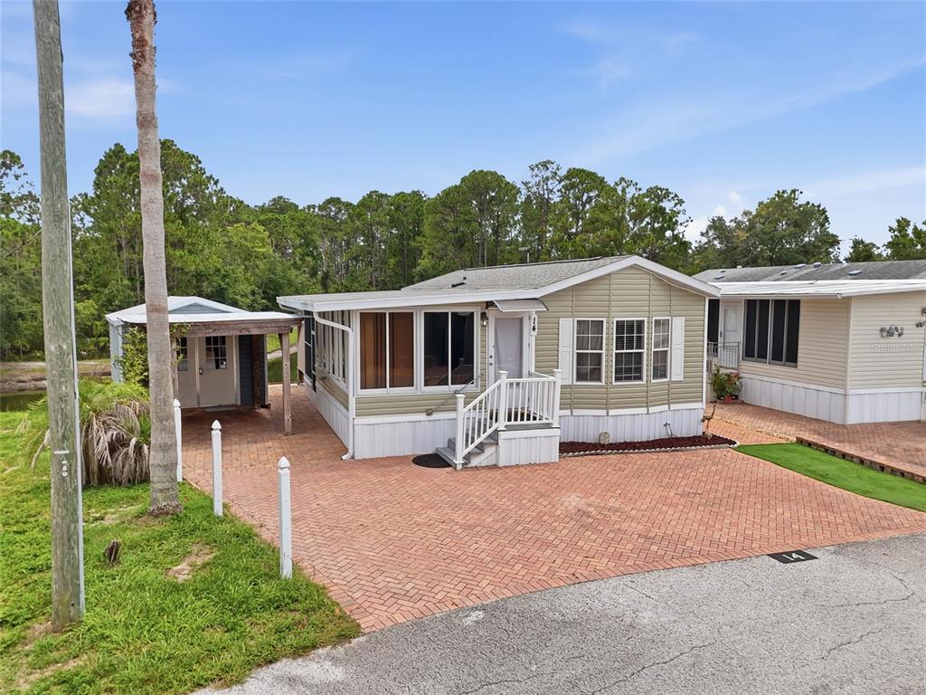 A light green manufactured home with a brick driveway and a detached carport — 20285 US HIGHWAY 27 UNIT 14, CLERMONT, FL