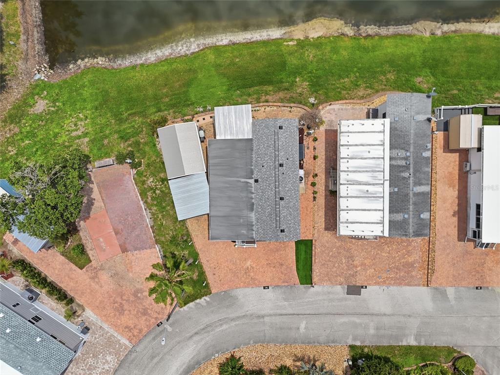 An aerial view shows a residential property with a paved driveway, roof structures, and waterfront access — 20285 US HIGHWAY 27 UNIT 14, CLERMONT, FL