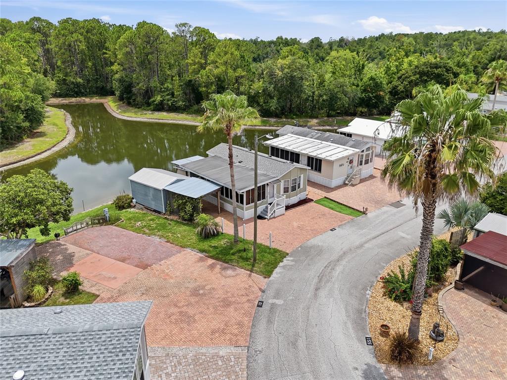 An aerial view shows two manufactured homes situated next to a pond and a road — 20285 US HIGHWAY 27 UNIT 14, CLERMONT, FL