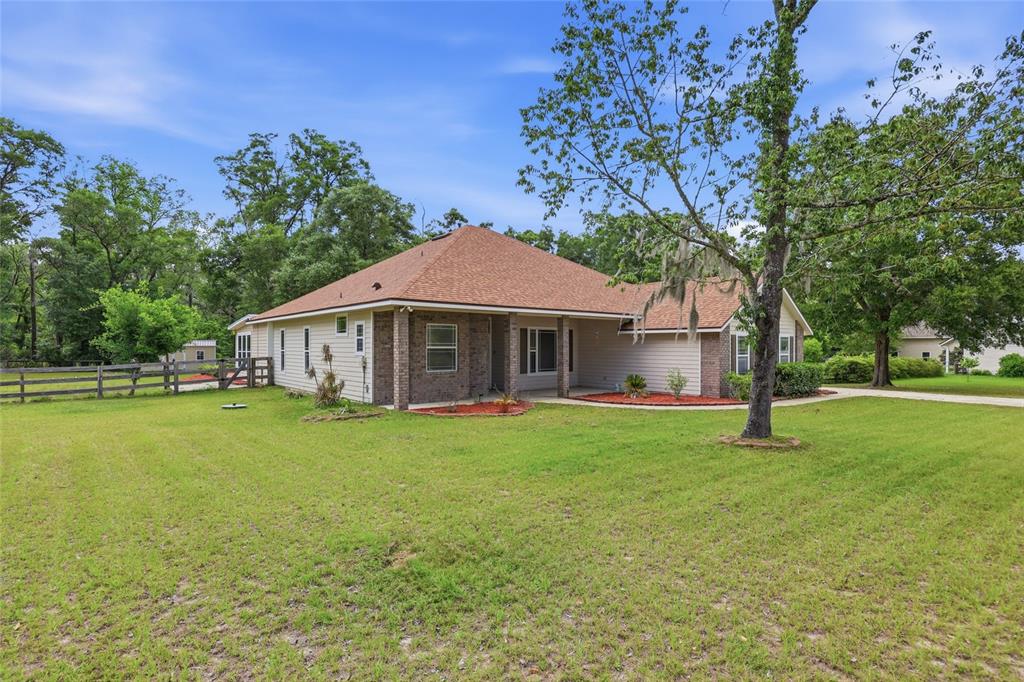 A single-story house with a brick and siding exterior sits on a large grassy lot — 25176 NW 209TH AVENUE, HIGH SPRINGS, FL