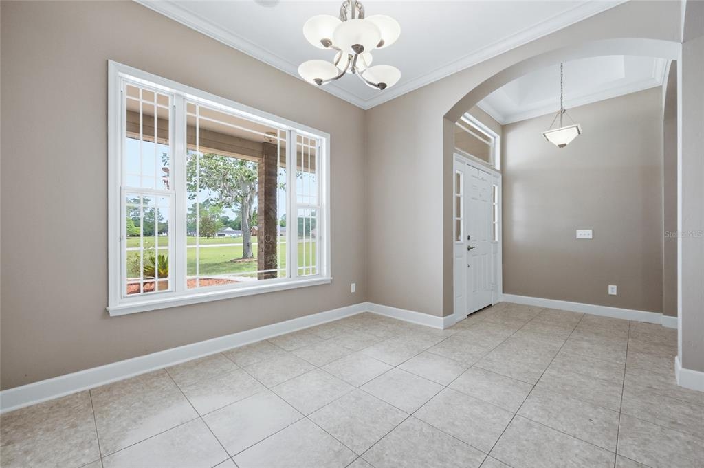 A bright dining area with tile floors, a chandelier, and a large window overlooking grass — 25176 NW 209TH AVENUE, HIGH SPRINGS, FL
