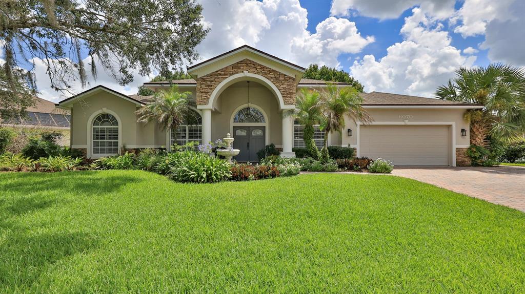 A single-story house with a stone-accented arched entryway, a two-car garage, and landscaped lawn — 6070 SABAL CREEK BOULEVARD, PORT ORANGE, FL