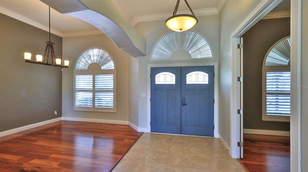 An entryway features blue double doors, tile flooring, and an adjacent room with wood floors — 6070 SABAL CREEK BOULEVARD, PORT ORANGE, FL