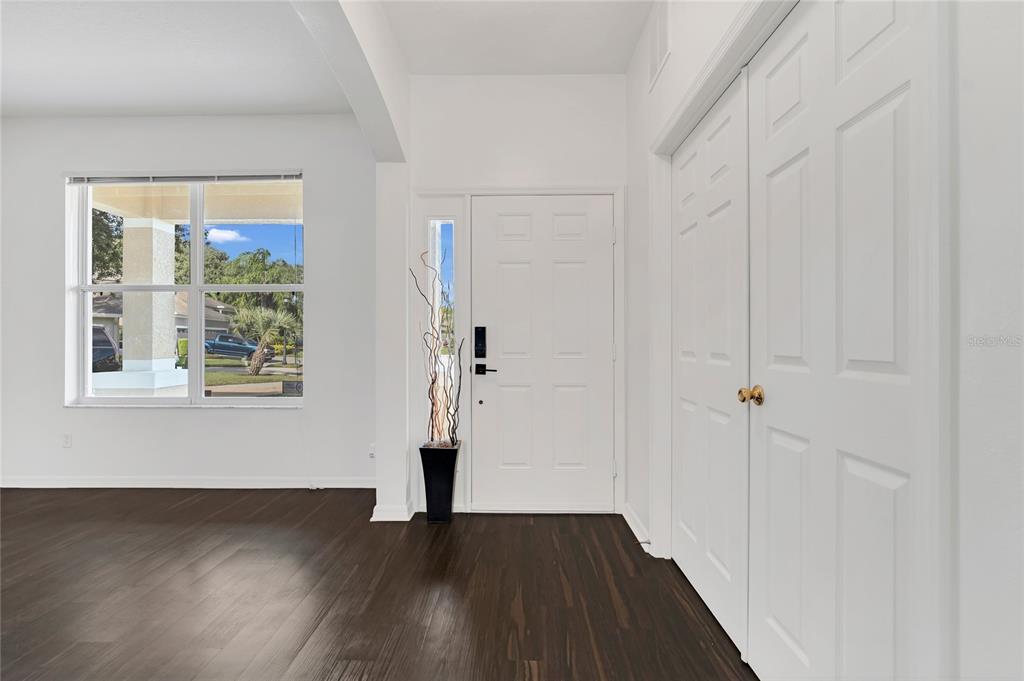An entryway features dark wood flooring, a white front door, and a double-door closet — 9531 OSPREY LANDING DRIVE, ORLANDO, FL