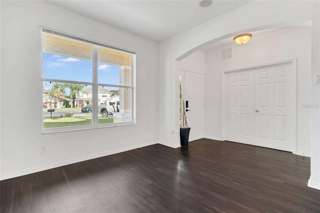 A bright room with dark wood flooring, a large window, and white double closet doors — 9531 OSPREY LANDING DRIVE, ORLANDO, FL