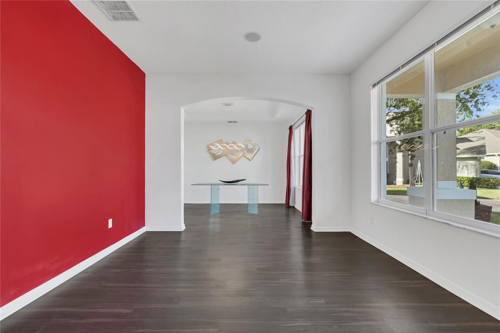 A room with dark wood flooring, a red accent wall, and an arched entryway — 9531 OSPREY LANDING DRIVE, ORLANDO, FL