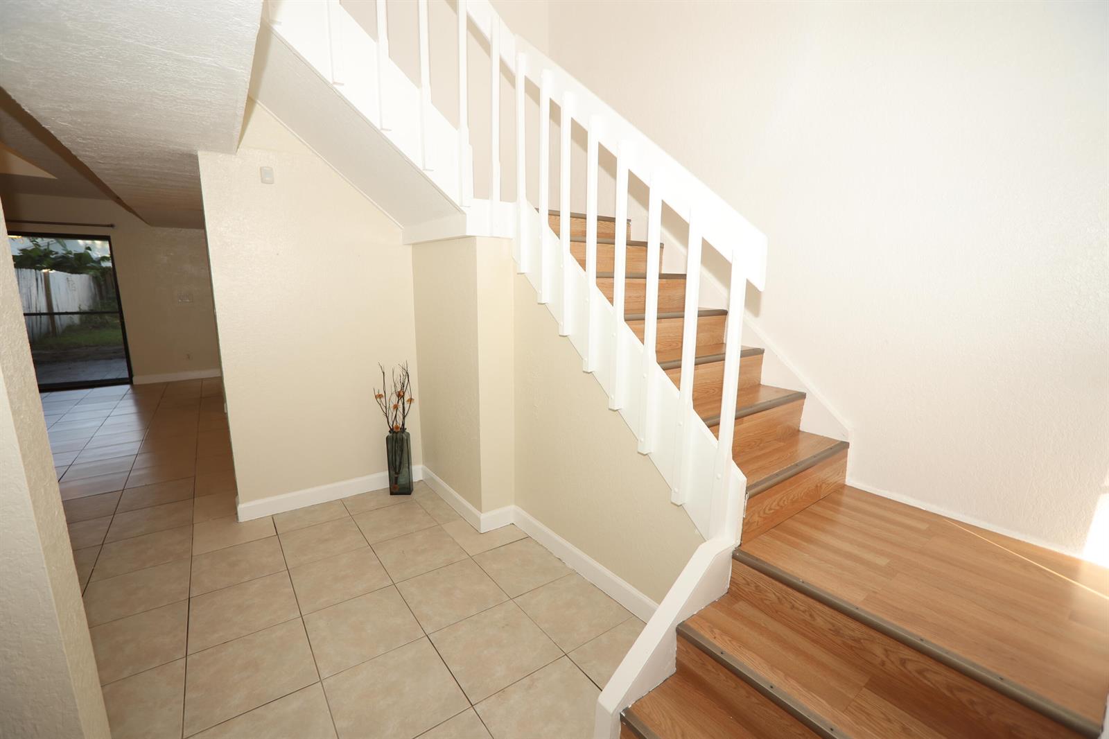 A staircase with wood treads and white railings sits next to a tiled entryway — 1265 The 12th Fairway, Wellington FL 33414, WELLINGTON, FL